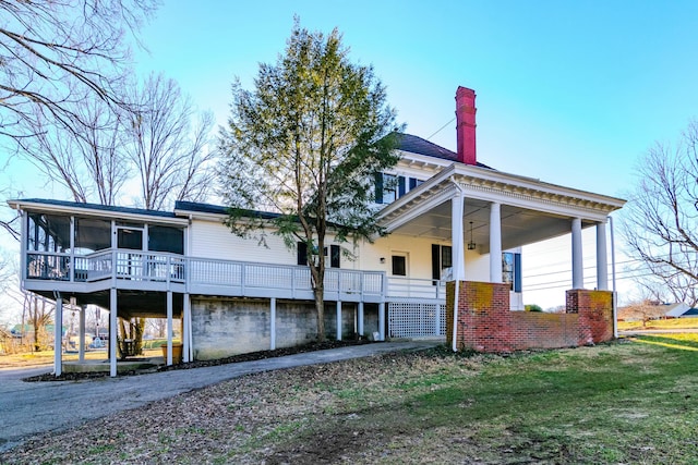 exterior space featuring a yard, a chimney, and a sunroom