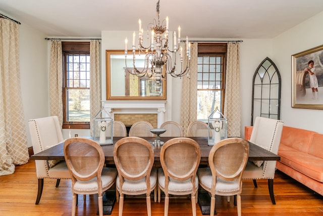 dining room featuring a notable chandelier, a fireplace, and wood finished floors