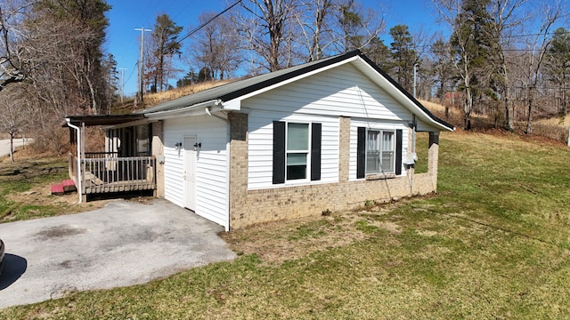 view of side of home with brick siding, a lawn, and driveway