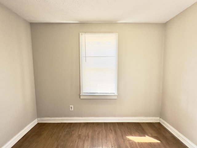 unfurnished room featuring baseboards and dark wood-style flooring