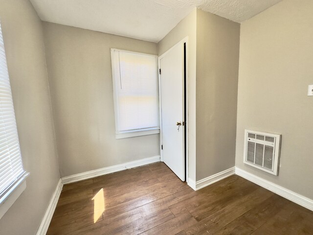 spare room with baseboards, visible vents, and dark wood-style flooring