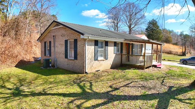 view of home's exterior featuring cooling unit, brick siding, metal roof, and a lawn