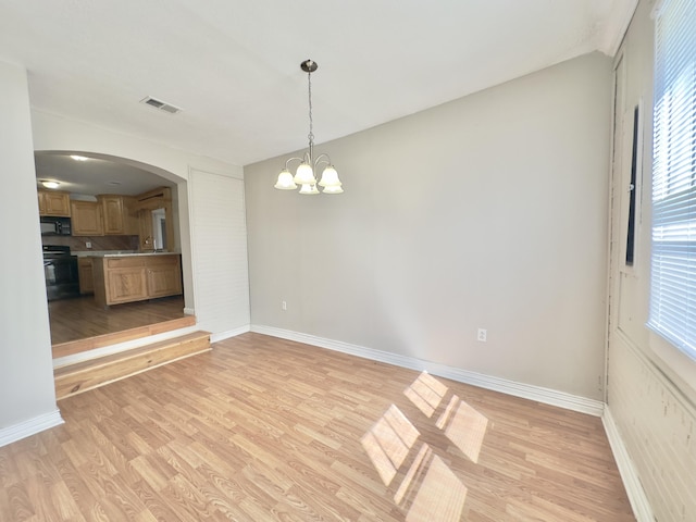 interior space featuring light wood-type flooring, baseboards, visible vents, and arched walkways