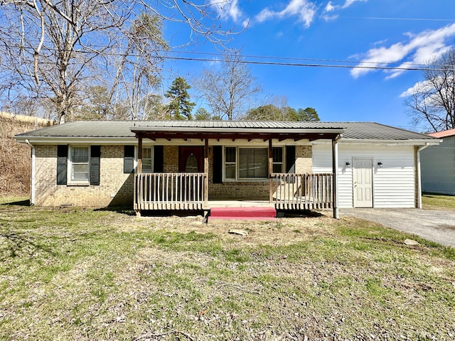 ranch-style house with covered porch, metal roof, aphalt driveway, and brick siding