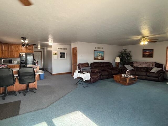 living area with light carpet, baseboards, visible vents, and a ceiling fan