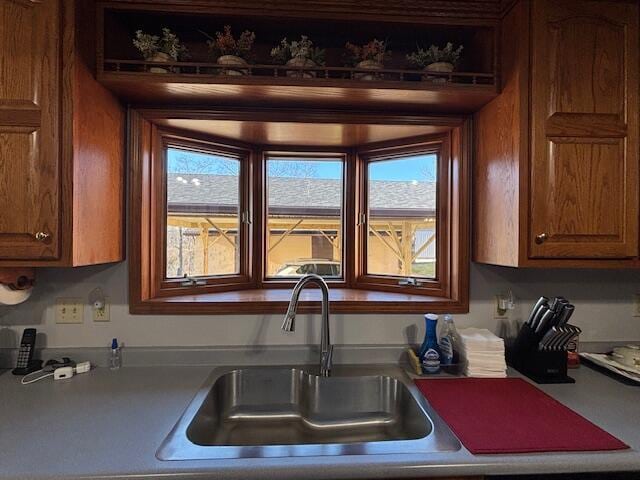 kitchen with brown cabinetry, a sink, and light countertops