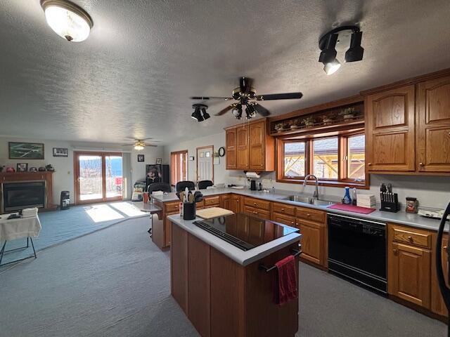 kitchen featuring open floor plan, a center island, light countertops, black appliances, and a sink