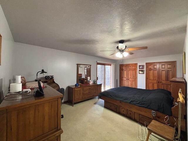 bedroom with multiple closets, a ceiling fan, light carpet, a textured ceiling, and access to outside