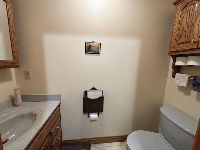 half bath with vanity, toilet, and baseboards