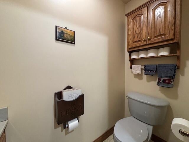 half bathroom featuring baseboards and toilet