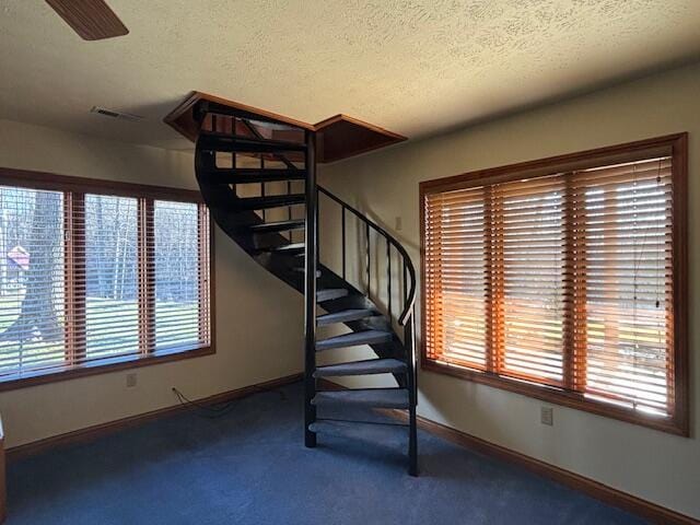 stairs featuring carpet floors, visible vents, a textured ceiling, and baseboards