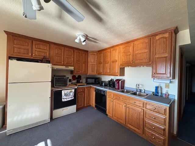 kitchen with a textured ceiling, under cabinet range hood, a sink, brown cabinets, and black appliances