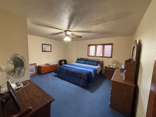 carpeted bedroom with ceiling fan and a textured ceiling