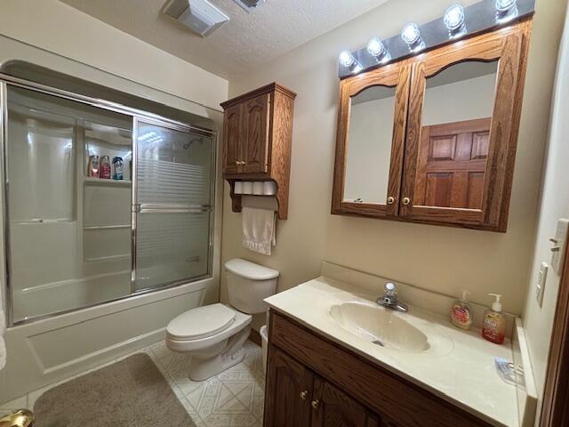 full bathroom with toilet, enclosed tub / shower combo, tile patterned floors, a textured ceiling, and vanity