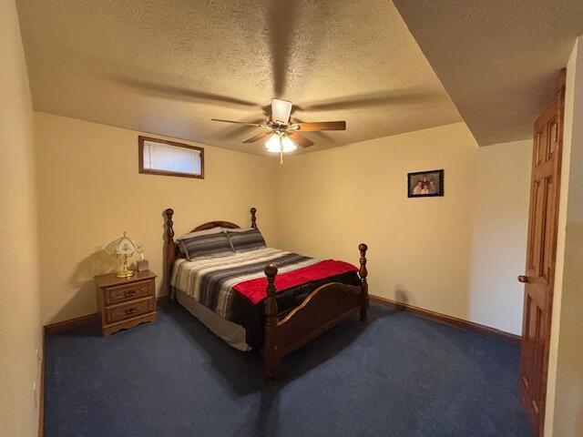 carpeted bedroom with a textured ceiling, ceiling fan, and baseboards