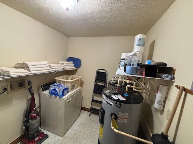 interior space with washer hookup, light floors, electric water heater, a textured ceiling, and laundry area