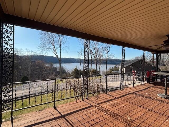 wooden deck with a water view and a ceiling fan