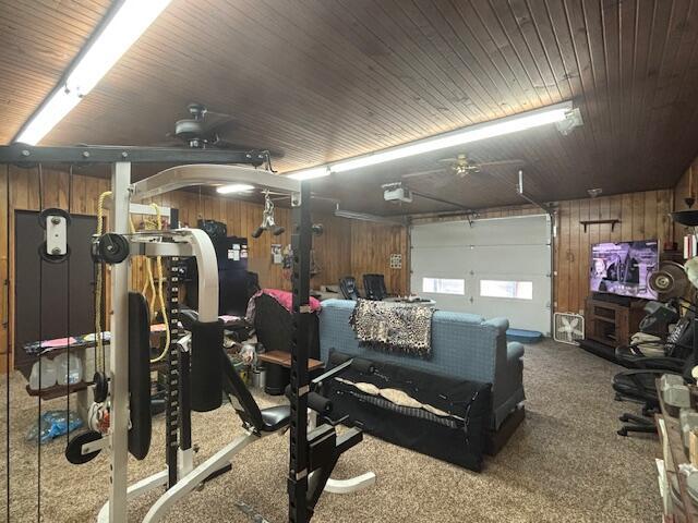 interior space with a garage, wooden ceiling, carpet flooring, and wood walls