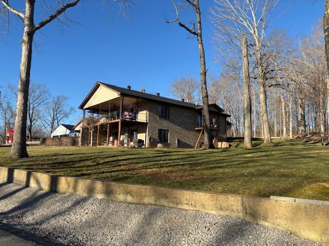 back of house featuring a yard and a balcony