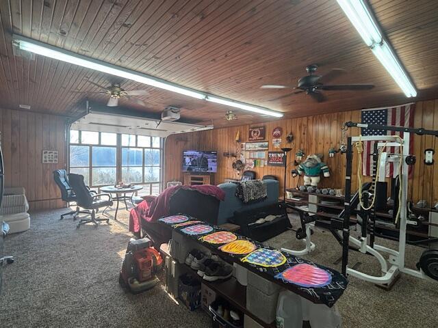 interior space featuring carpet floors, wood walls, wood ceiling, and a ceiling fan