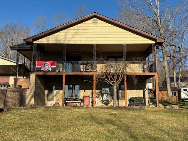 back of property with a yard and a balcony