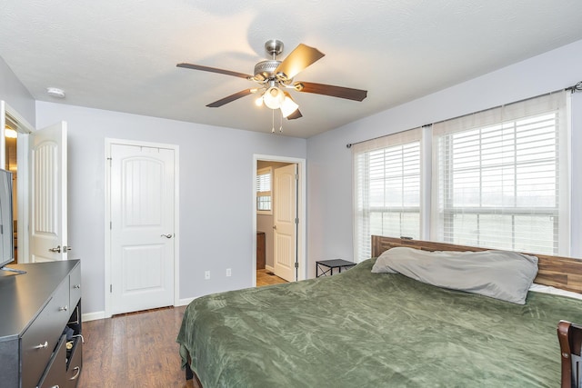 bedroom featuring dark wood-style flooring, ensuite bathroom, a ceiling fan, a textured ceiling, and baseboards