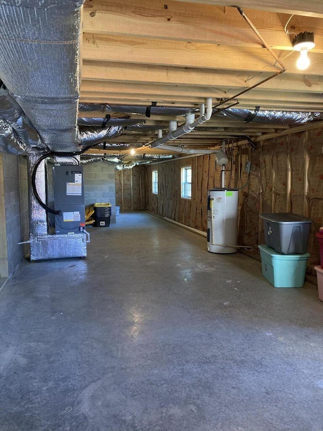 basement with concrete block wall, water heater, and heating unit