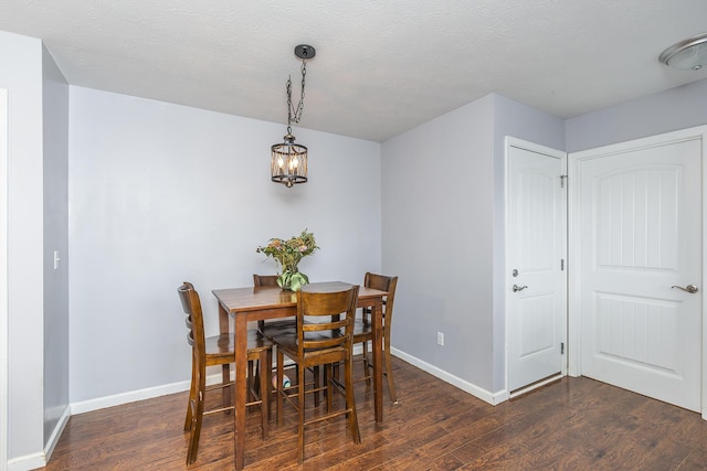 dining area with a chandelier, a textured ceiling, wood finished floors, and baseboards