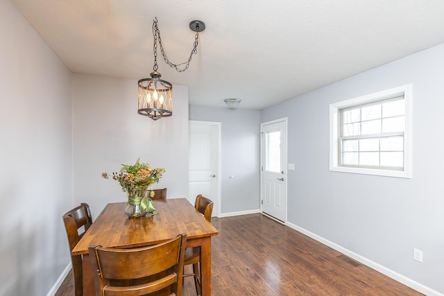 dining room featuring dark wood-type flooring, a chandelier, visible vents, and baseboards