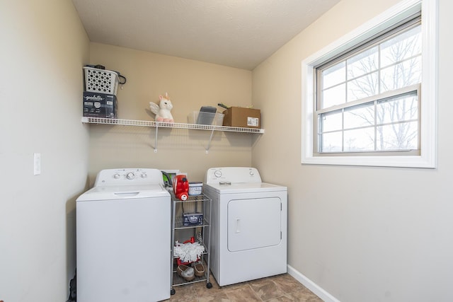 clothes washing area with laundry area, washing machine and dryer, and baseboards