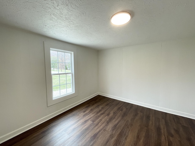 spare room with dark wood-style floors, baseboards, and a textured ceiling