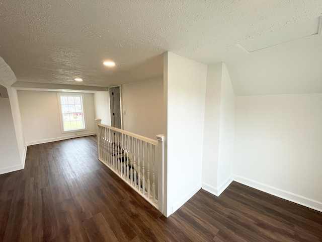 bonus room featuring a textured ceiling, lofted ceiling, baseboards, and wood finished floors