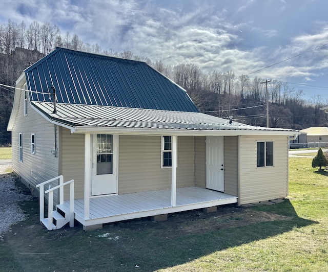 back of house featuring metal roof and a yard