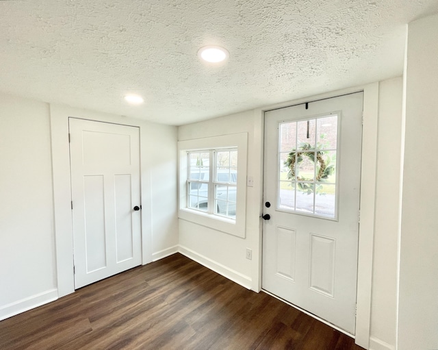 foyer entrance featuring baseboards, dark wood-type flooring, and a textured ceiling