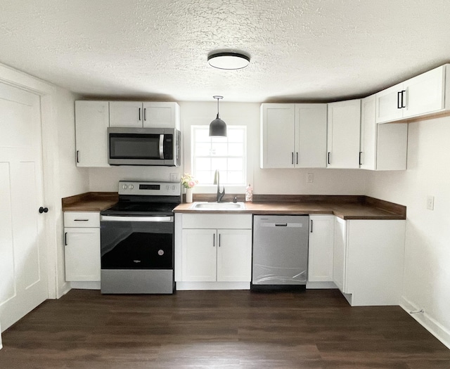 kitchen with dark wood finished floors, white cabinets, appliances with stainless steel finishes, and a sink