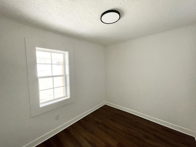 unfurnished room with baseboards, dark wood-style flooring, and a textured ceiling