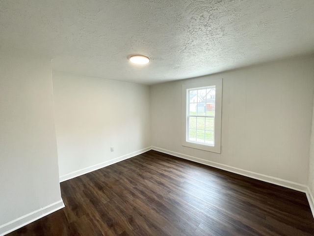 empty room with dark wood-style floors, baseboards, and a textured ceiling