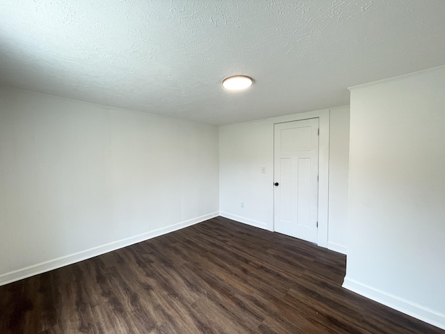 unfurnished room featuring dark wood-type flooring, baseboards, and a textured ceiling