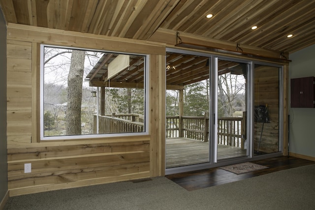 doorway to outside featuring plenty of natural light, visible vents, and wooden walls