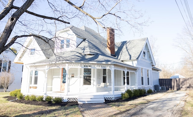 view of front of property featuring roof with shingles, a chimney, a porch, fence, and cooling unit