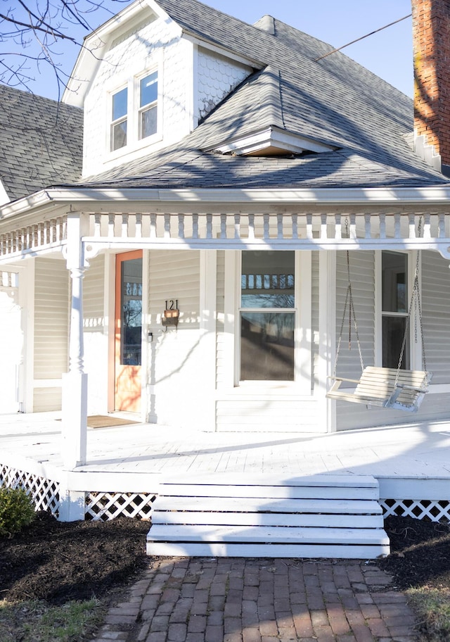 view of home's exterior featuring covered porch and a shingled roof