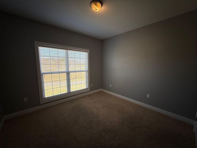 unfurnished room featuring carpet flooring, visible vents, and baseboards