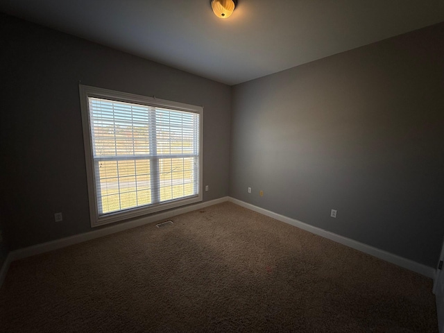 unfurnished room with carpet, visible vents, and baseboards