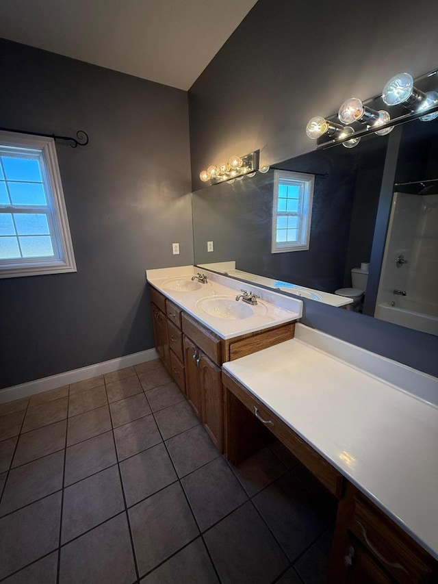 bathroom with toilet, a sink, baseboards, tile patterned floors, and double vanity