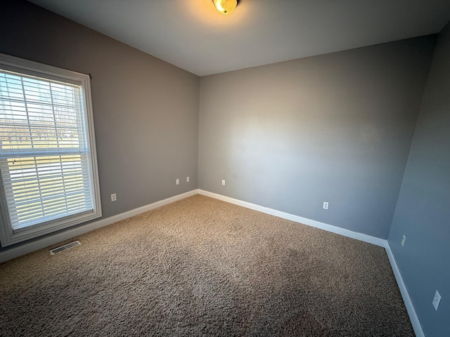 empty room with baseboards, visible vents, and carpet flooring