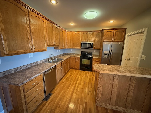 kitchen featuring brown cabinets, stainless steel appliances, recessed lighting, a sink, and light wood-type flooring