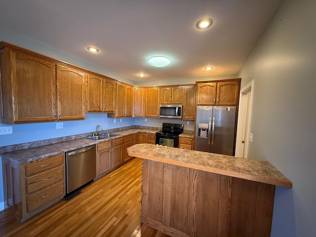 kitchen with recessed lighting, a sink, light wood-style floors, appliances with stainless steel finishes, and brown cabinets