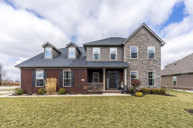 view of front of home with a porch, brick siding, a front lawn, and roof with shingles