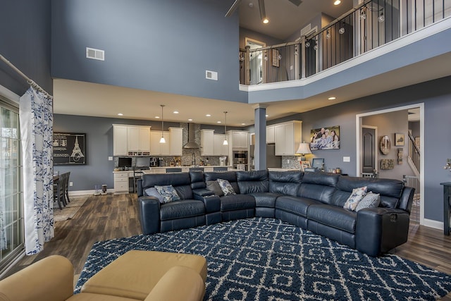 living room featuring dark wood-style floors, stairs, visible vents, and baseboards