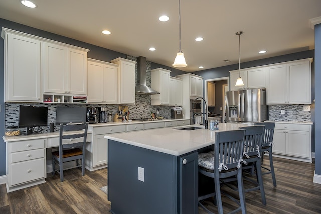 kitchen featuring a sink, appliances with stainless steel finishes, dark wood-style flooring, and wall chimney range hood